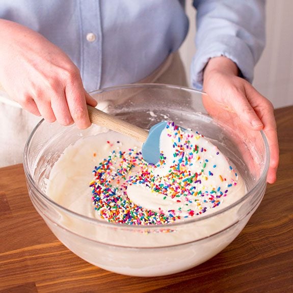 funfetti cake recipe, colorful sprinkles being stirred into batter
