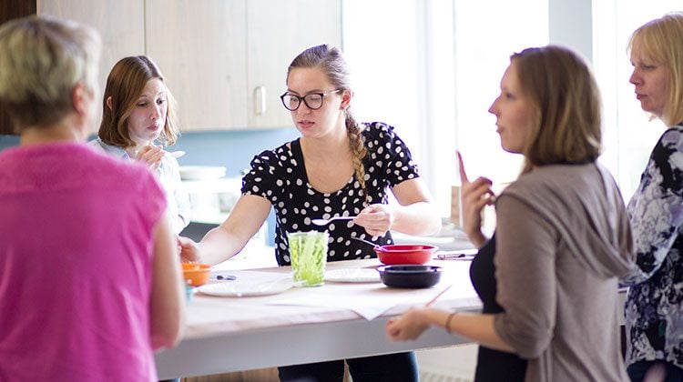 Professional taste testers standing around a table in a bright kitchen with bowls of yogurt and papers in front of everyone